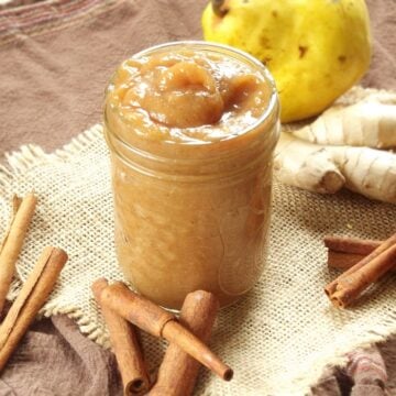 Jar of Pear Butter surrounded by cinnamon sticks and fresh ginger.