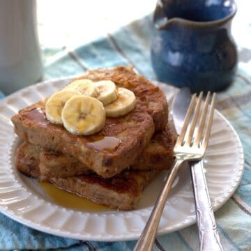 Plate of Vegan Peanut Butter Banana French Toast topped with syrup and banana slices.