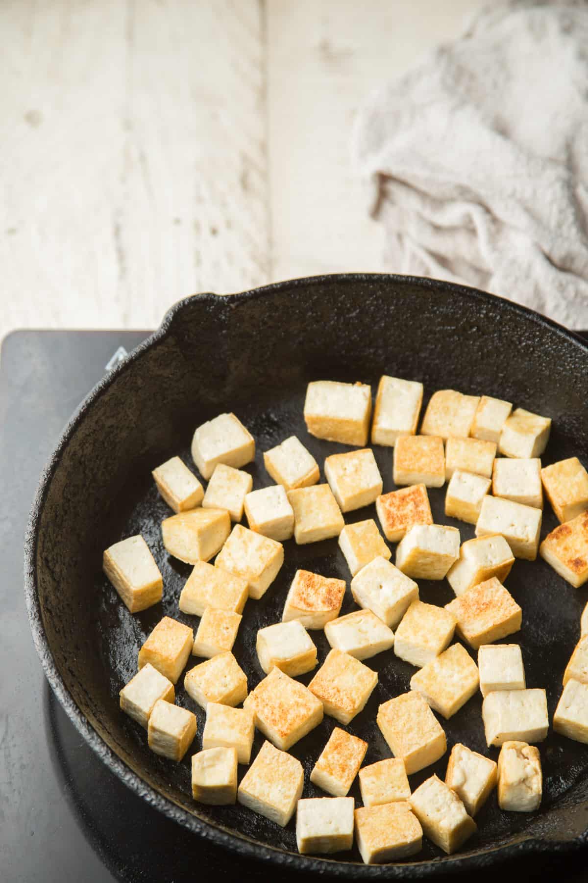Tofu cubes cooking in a skillet.
