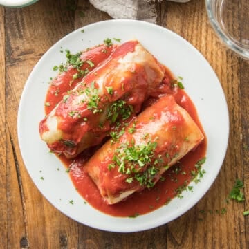 Two Vegan Cabbage Rolls on a plate with parsley on top.