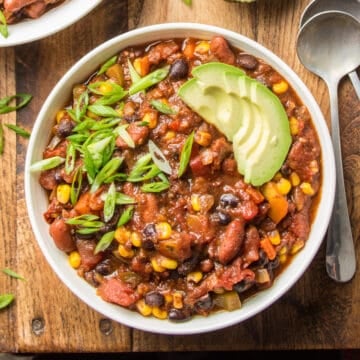 Bowl of Vegan Chili topped with scallions and avocado slices.