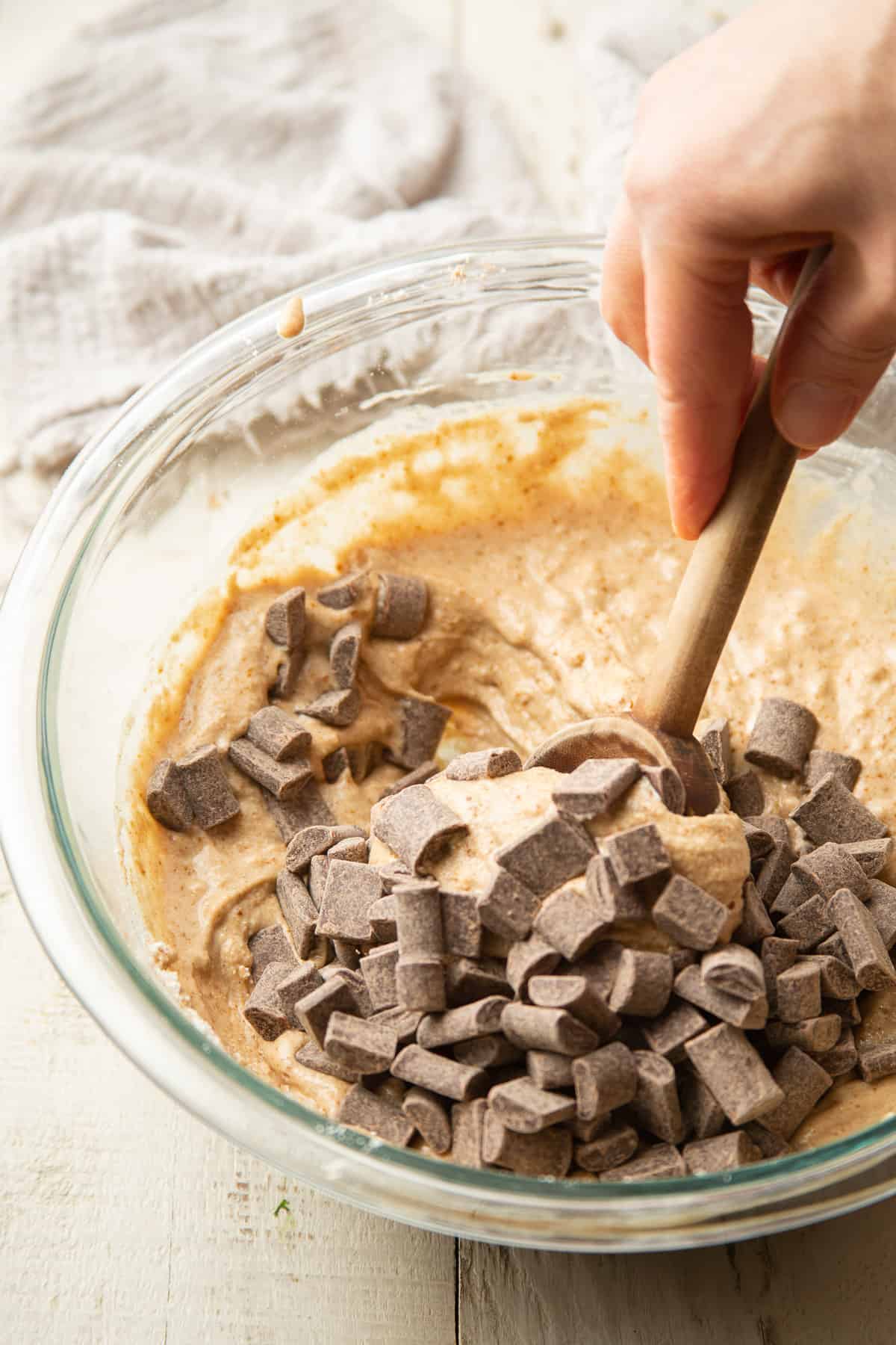Hand stirring chocolate chips into muffin batter.