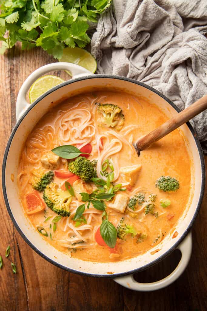 Olla de sopa de fideos al curry rojo con cuchara de madera.