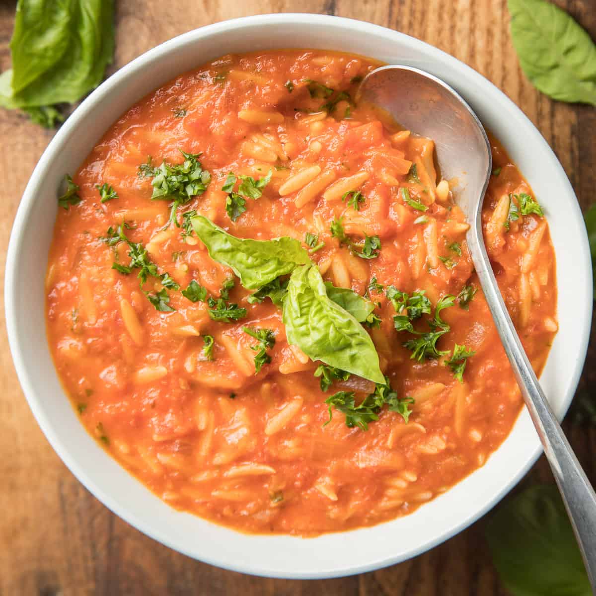 Tazón de sopa de tomate y orzo con cuchara.