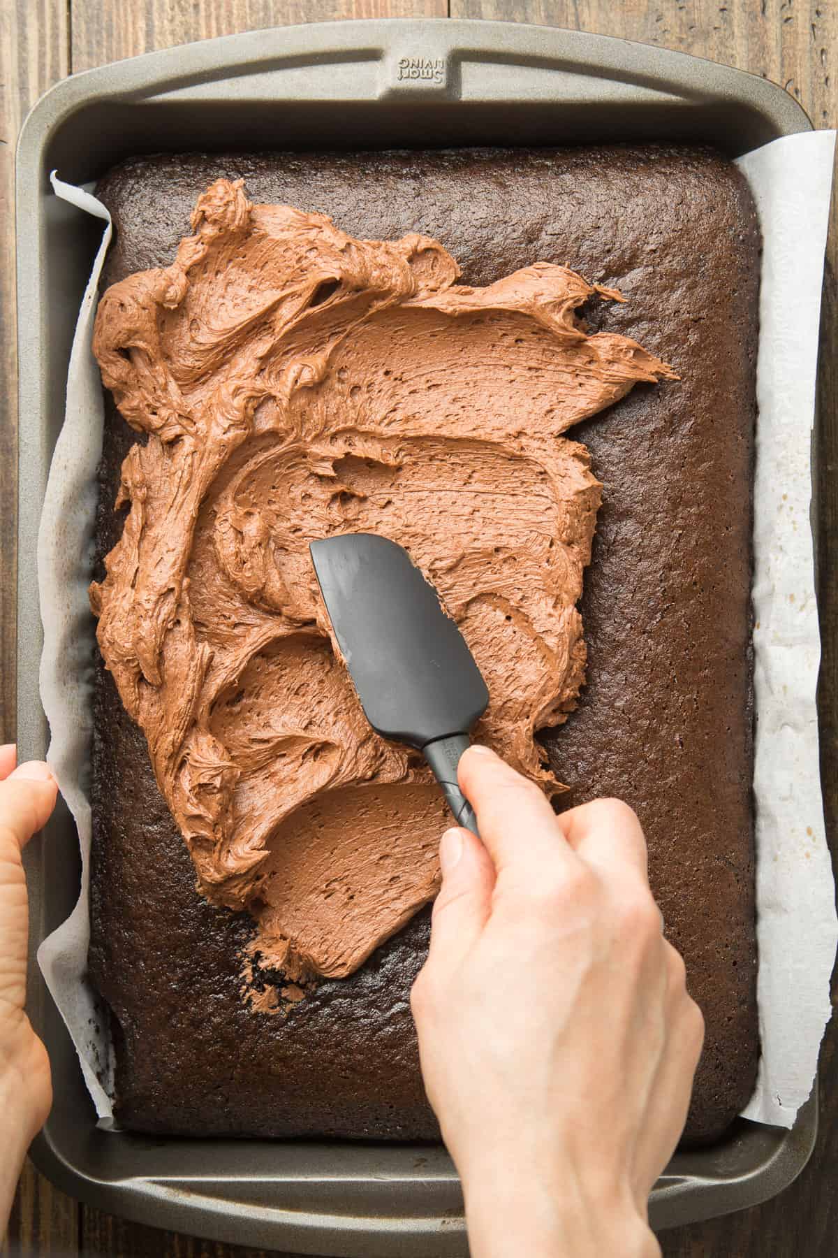Hand Using a Spatula to Frost a Vegan Chocolate Sheet Cake.