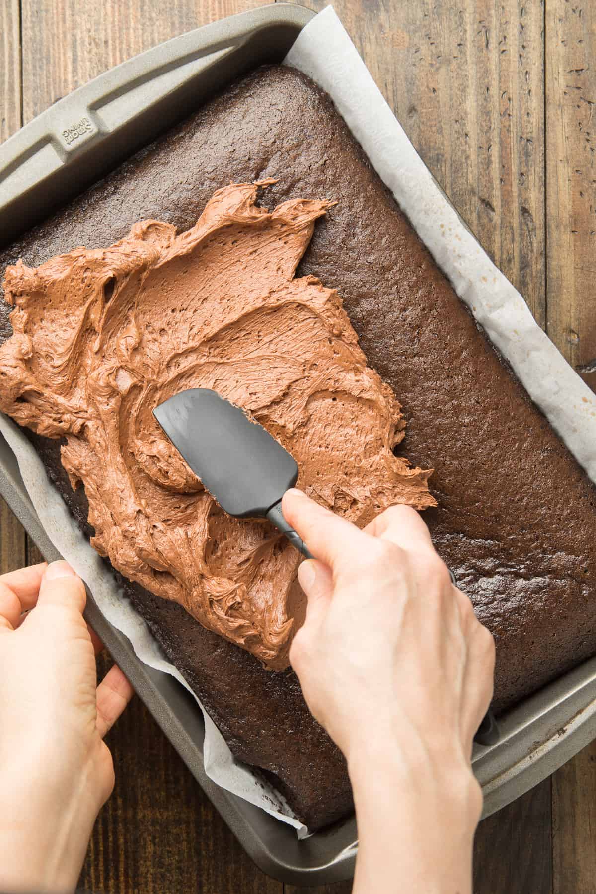 Hand Using a Spatula to Frost a Vegan Chocolate Sheet Cake.