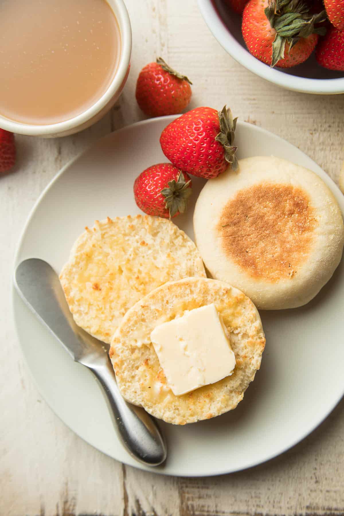 Plate with two Vegan English Muffins, butter, and strawberries.