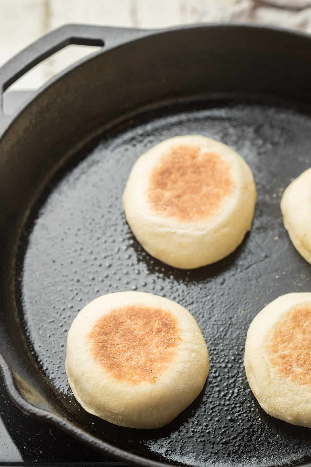 Vegan English Muffins cooking in a skillet.