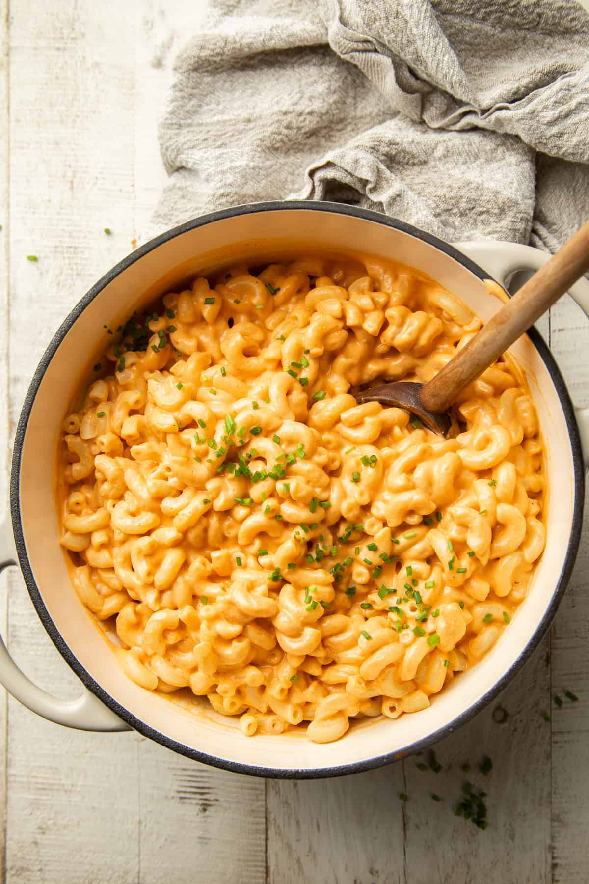 Pot of Vegan Mac & Cheese with wooden spoon and chives on top.