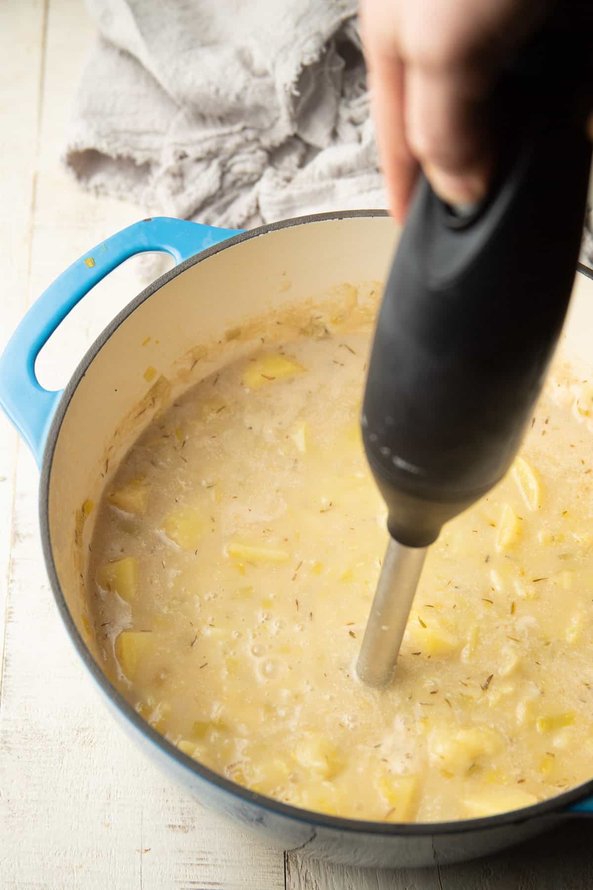 Hand blending Vegan Potato Leek Soup with an immersion blender.