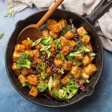 Skillet of General Tso's Tofu with wooden spoon.