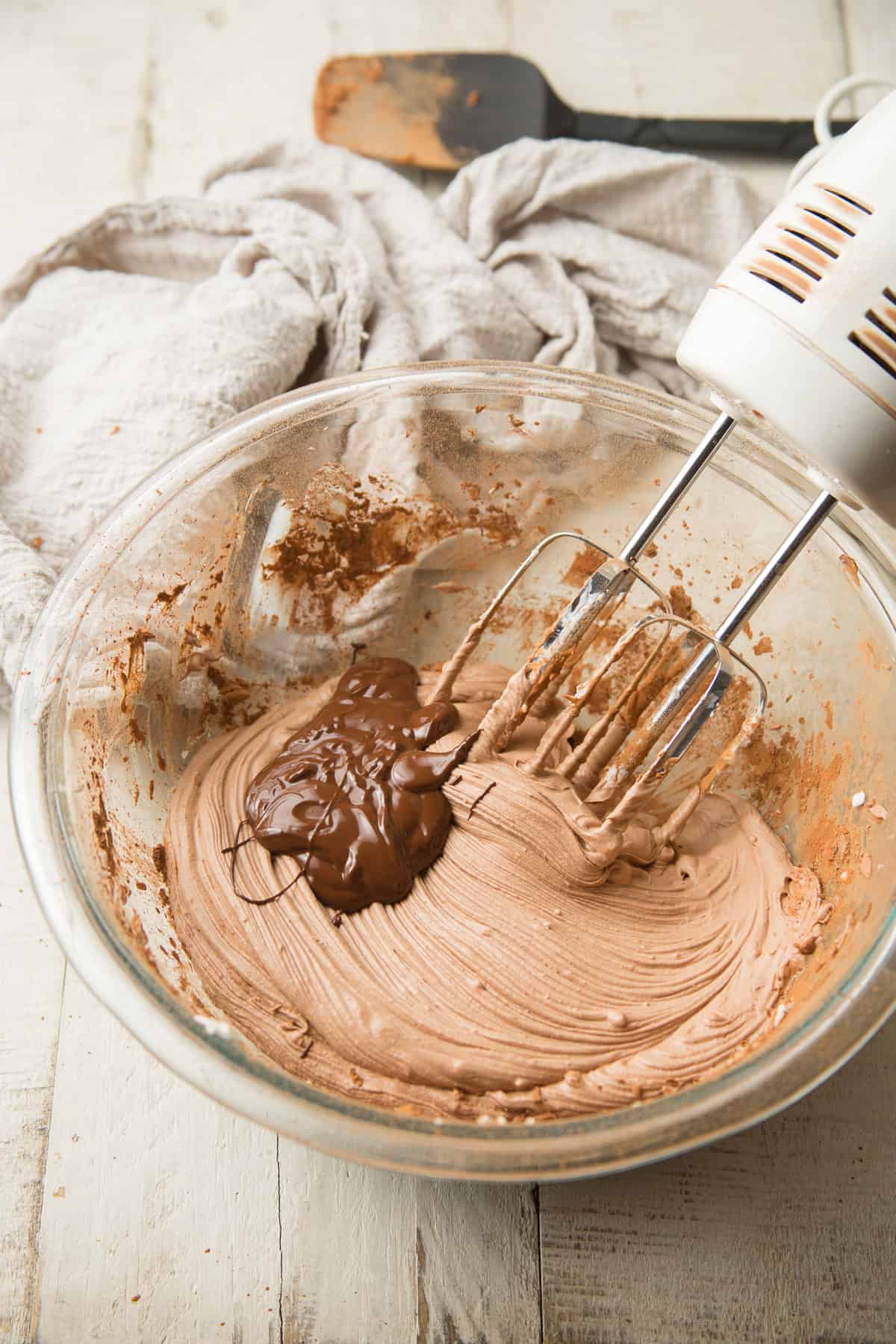 Bowl of Vegan Chocolate Mousse with electric mixer and melted chocolate being added.