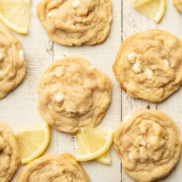 Vegan Lemon Cookies arranged on a white wooden surface with lemon slices.