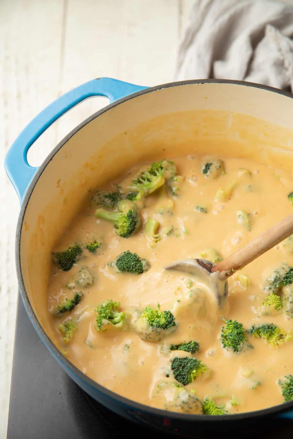 Sopa vegana de brócoli y queso cheddar hirviendo a fuego lento en una olla.