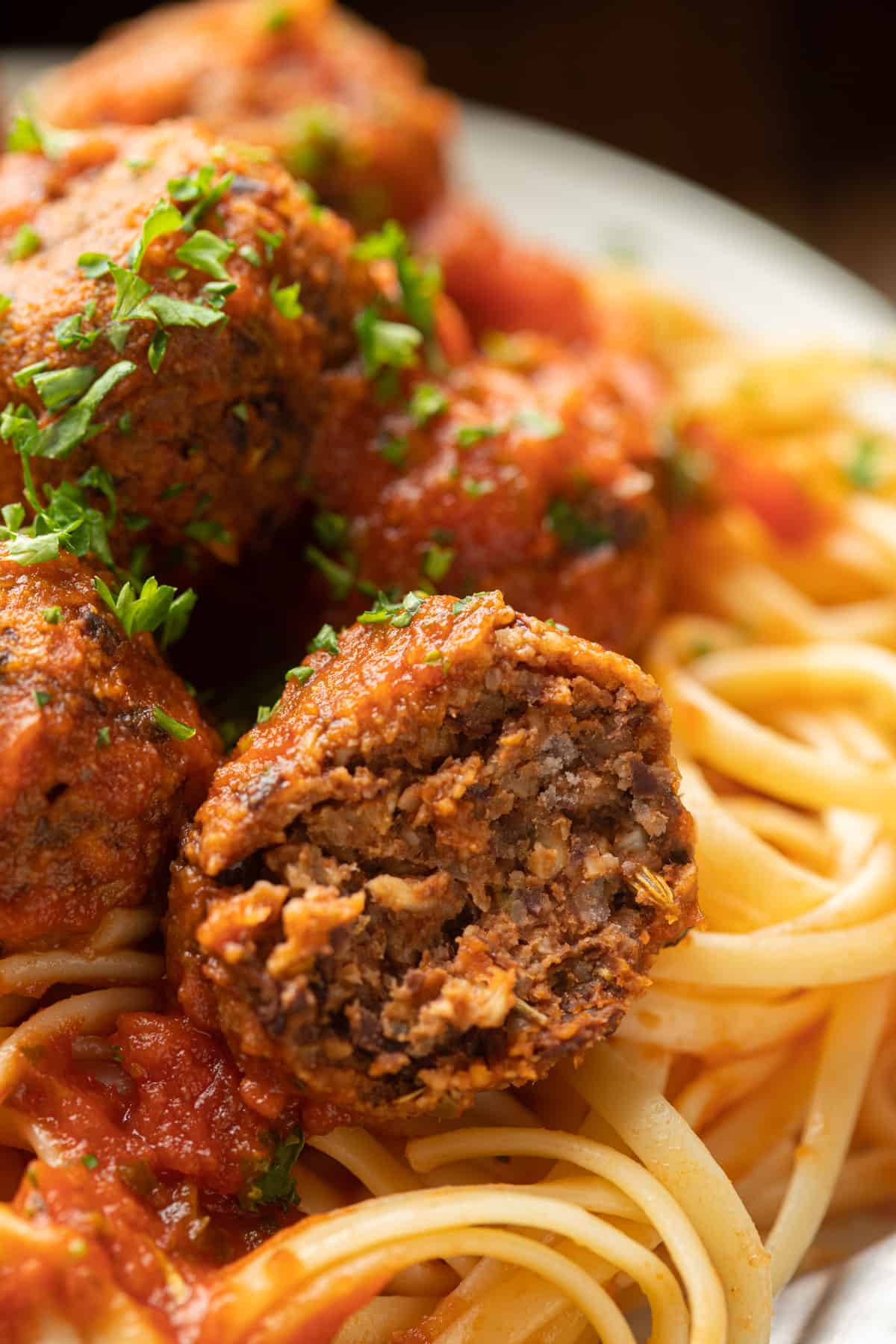 Close up of half a Vegan Meatball on top of spaghtetti.