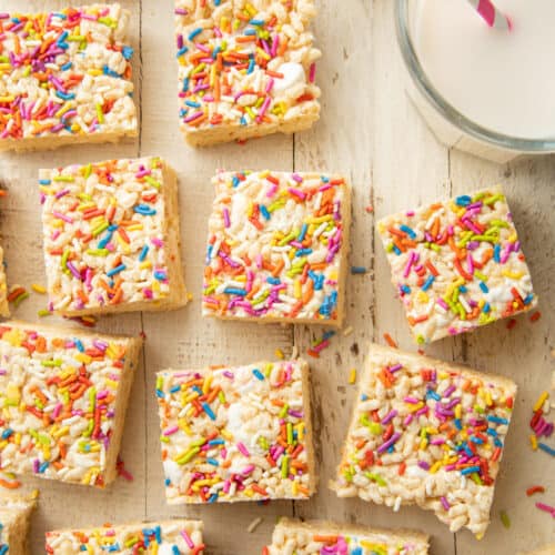 Vegan Rice Krispie Treats on a White Wooden Surface with Glass of Almond milk.