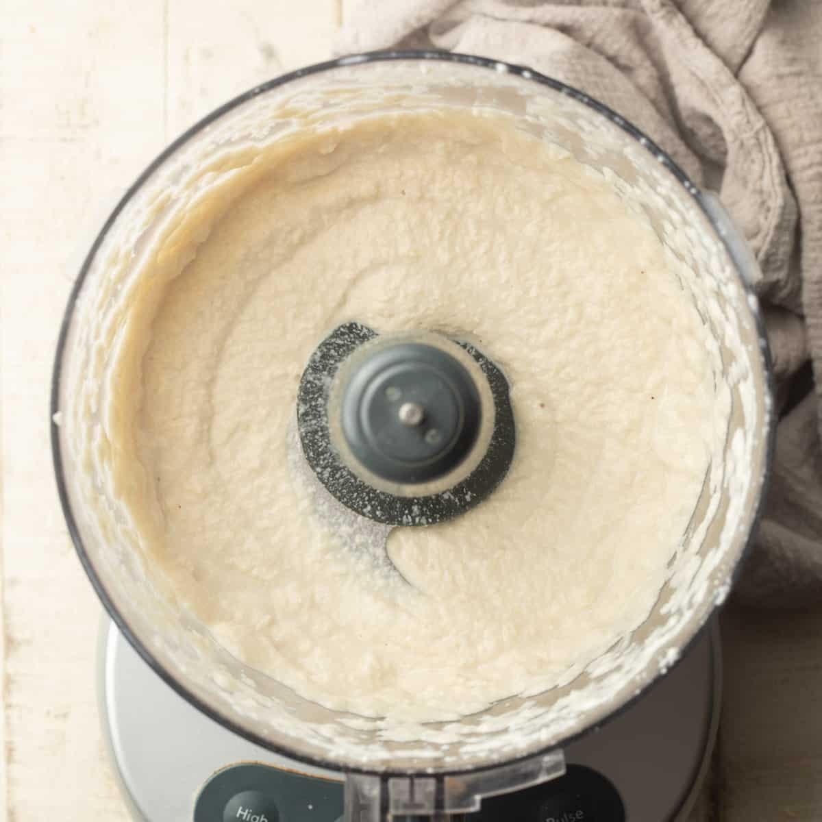 Food processor bowl filled with cashew cream mixture for making vegan ricotta.