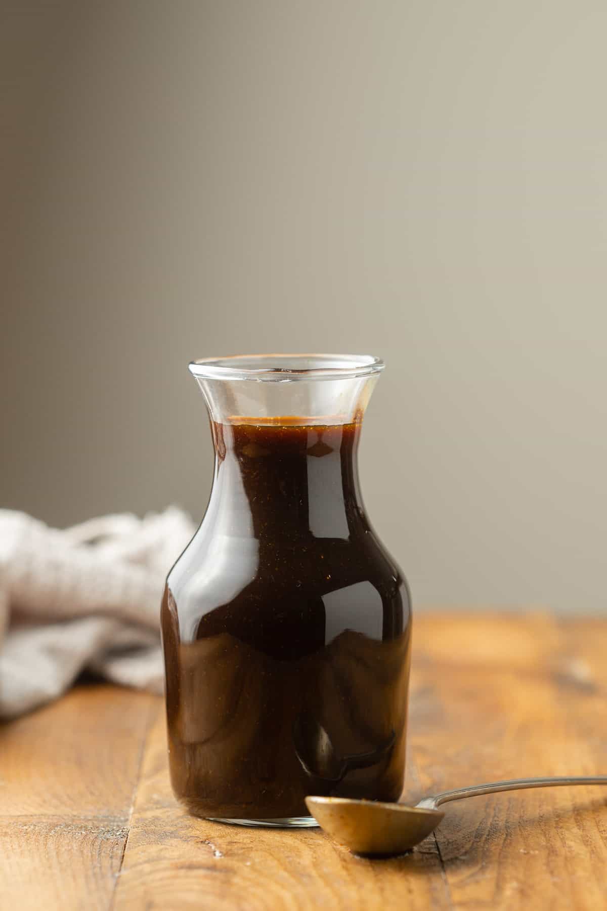 Bottle of Vegan Worcestershire Sauce with spoon in the foreground.