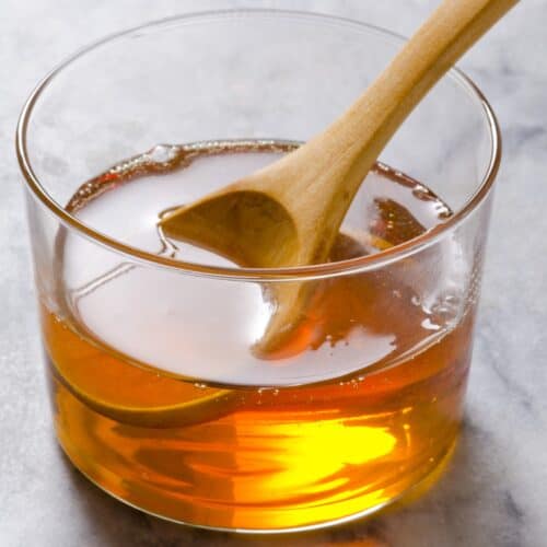 Glass of agave nectar with a wooden spoon in it.