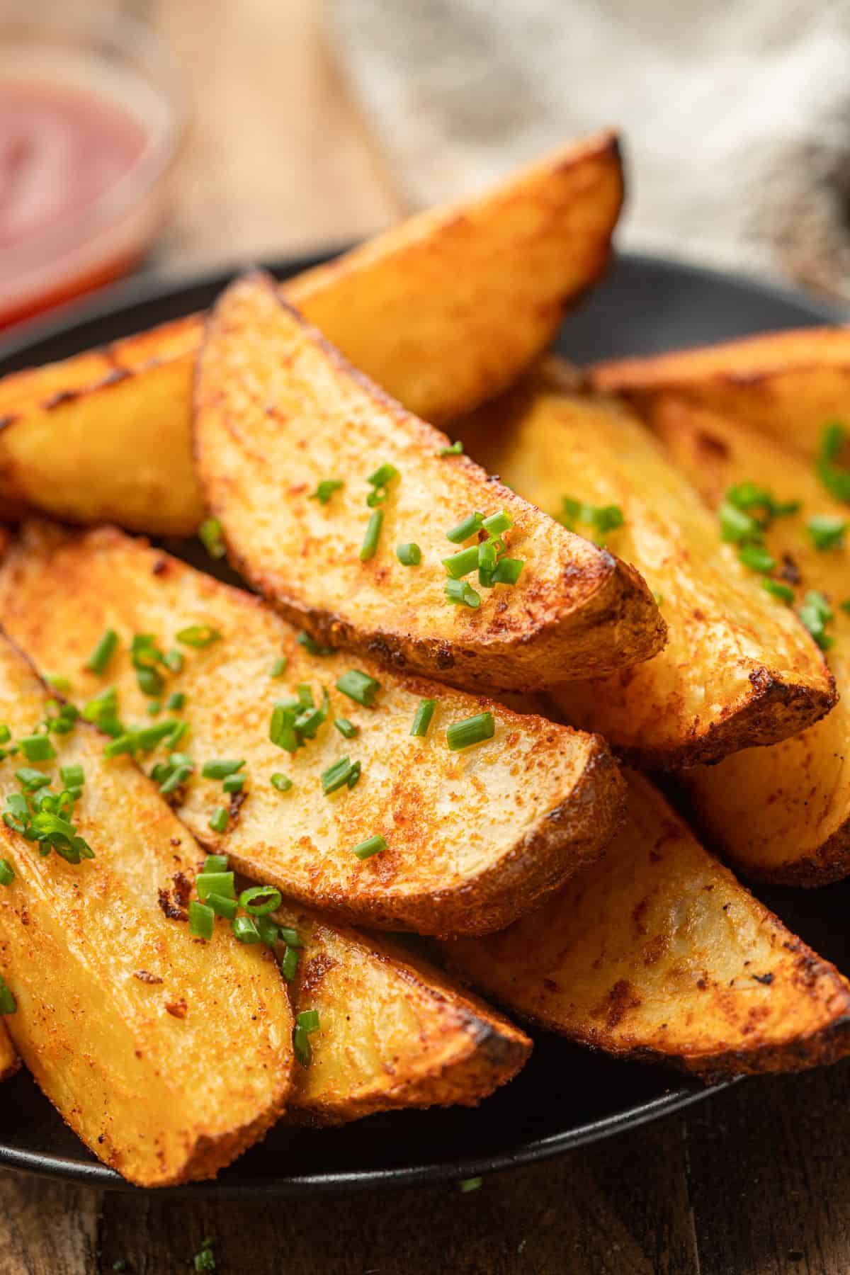 Air Fryer Potato Wedges on a plate with dish of ketchup in the background.