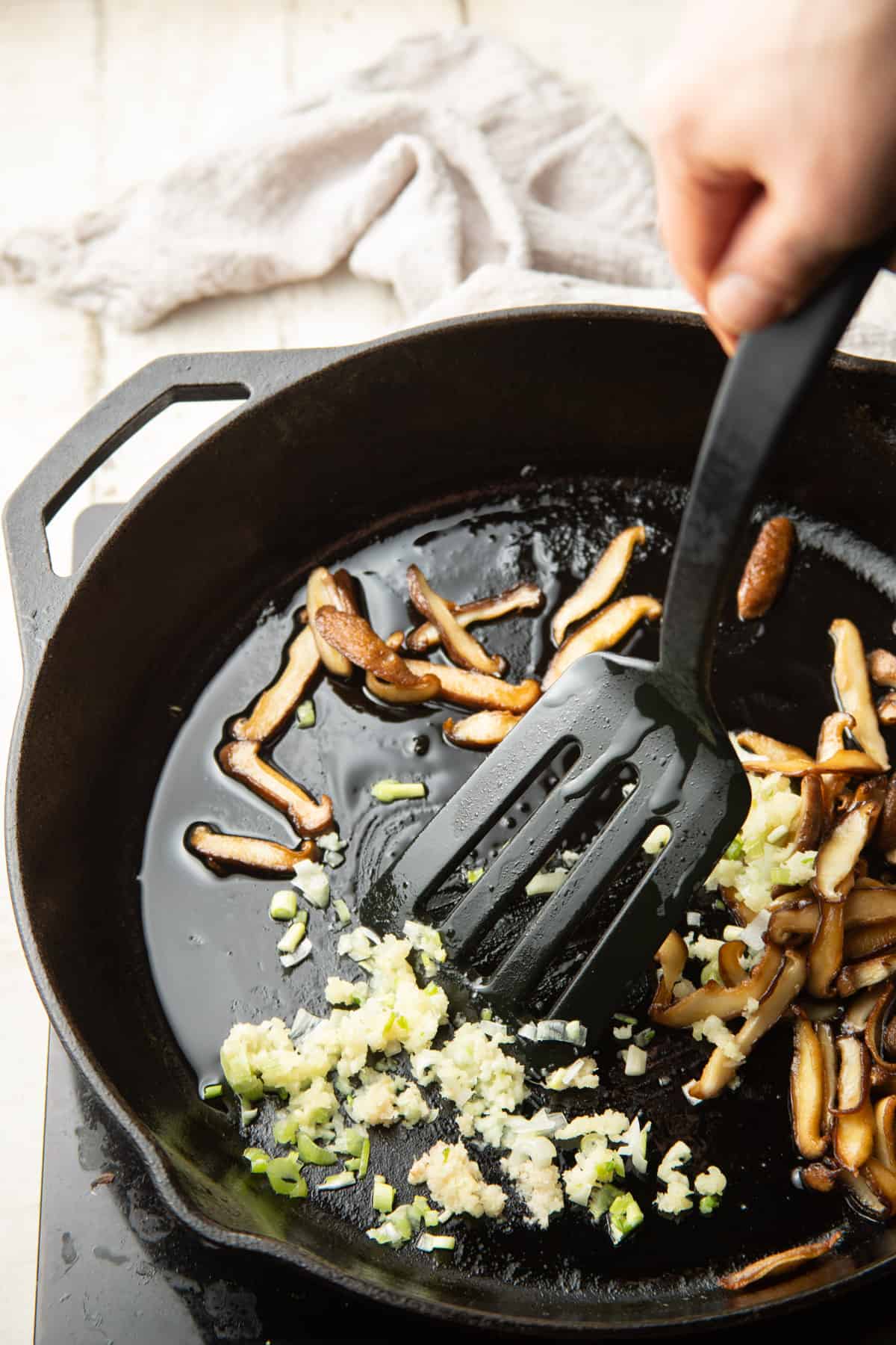 Mushrooms, garlic, ginger, and scallions cooking in a skillet.