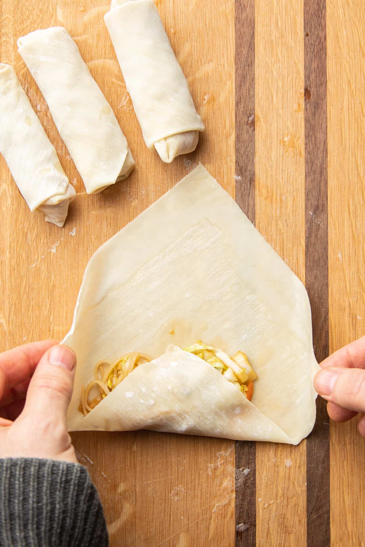 Pair of hands rolling a spring roll.