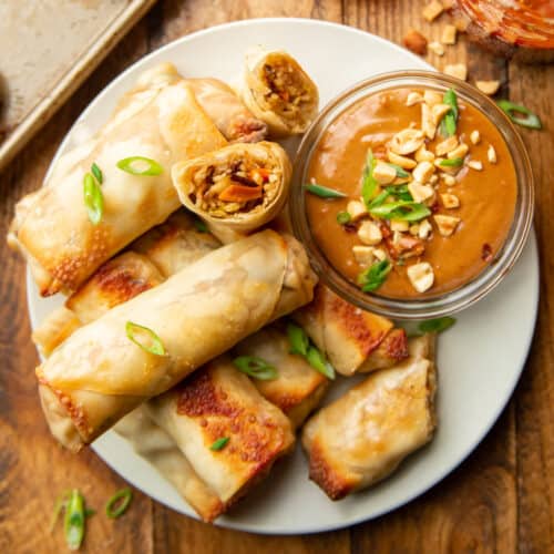 Plate of baked spring rolls with a dish of peanut sauce.