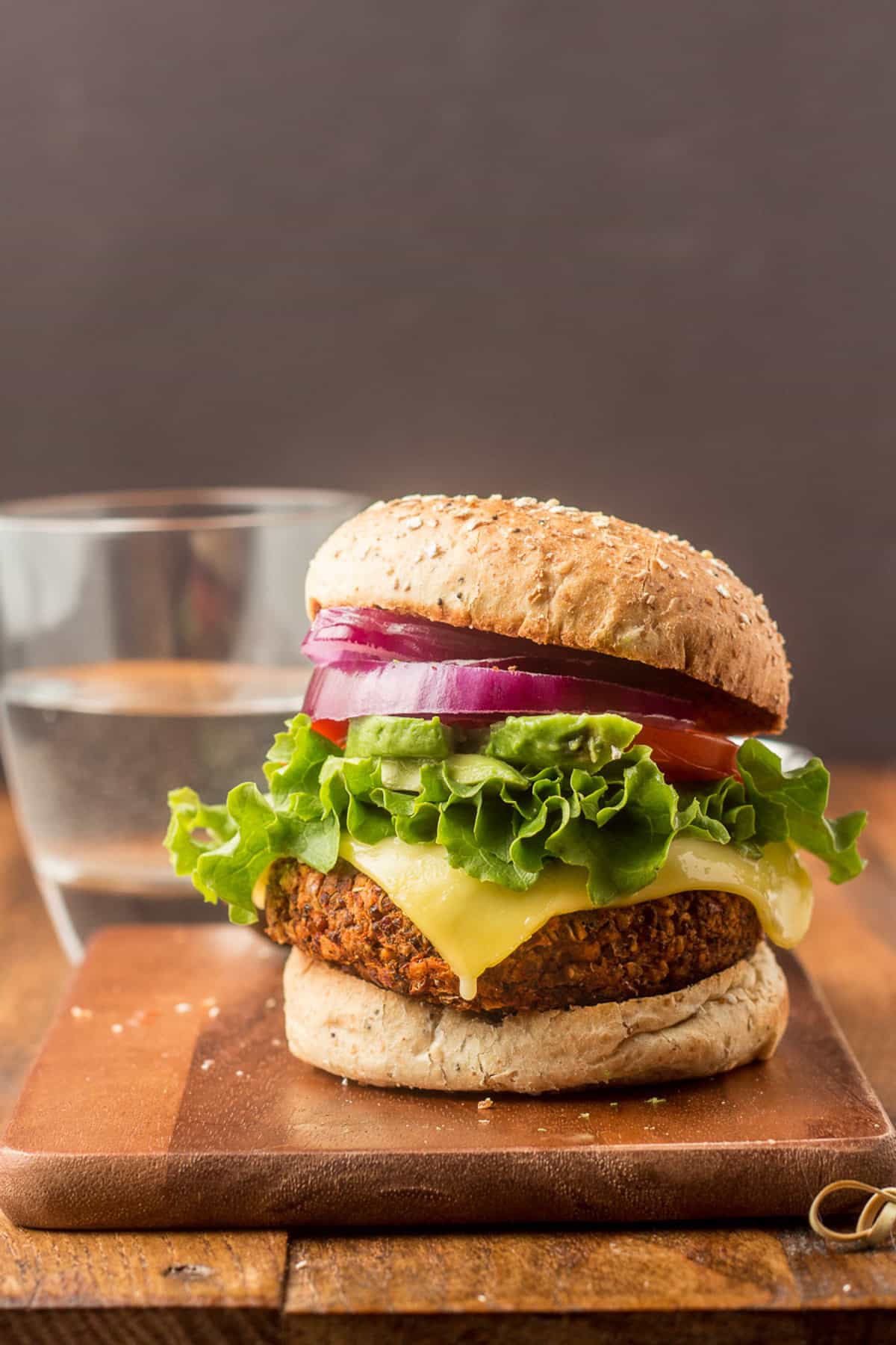 Quinoa burger on a cutting board with a glass of water in the background.