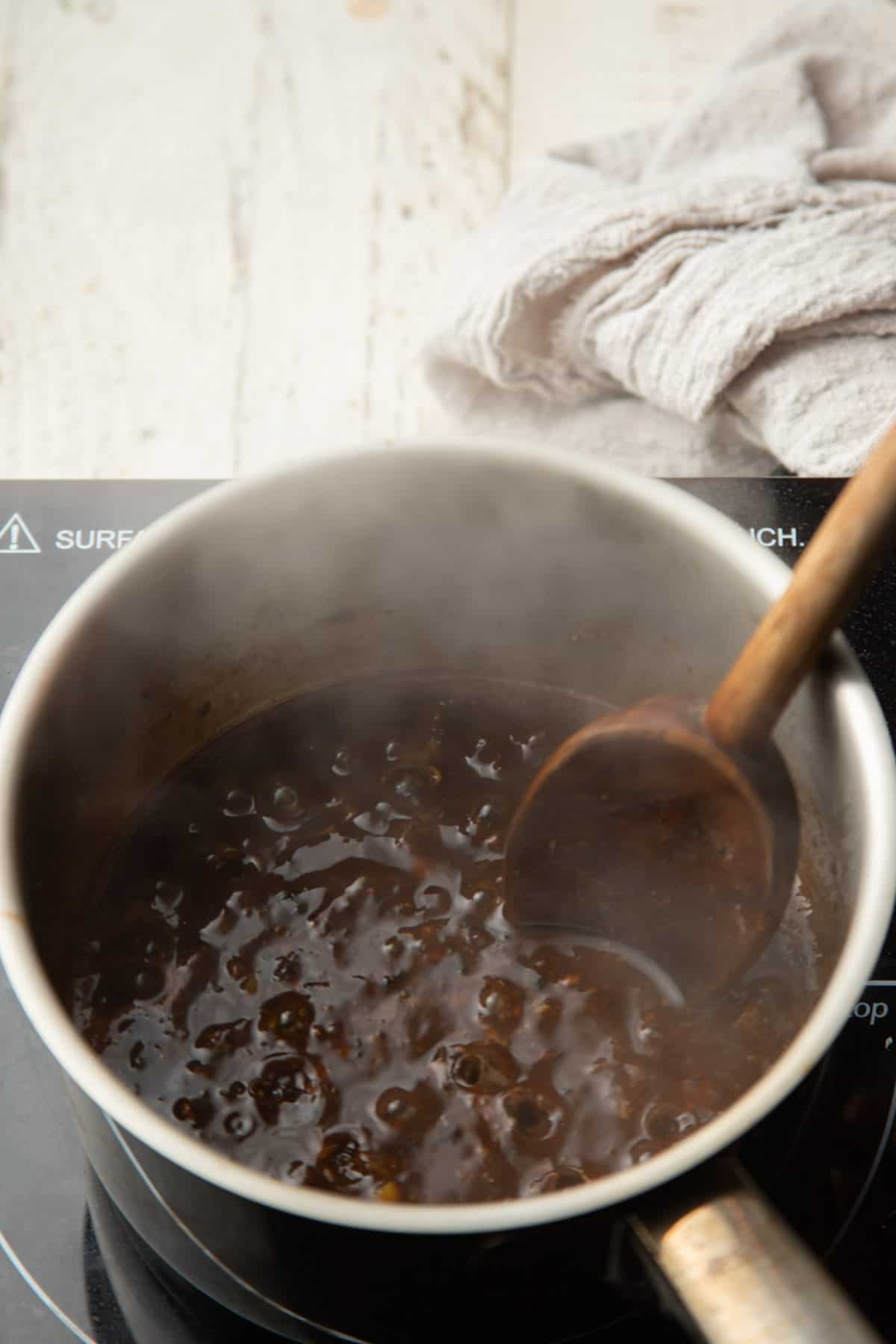 Thickened black bean sauce simmering in a saucepan.