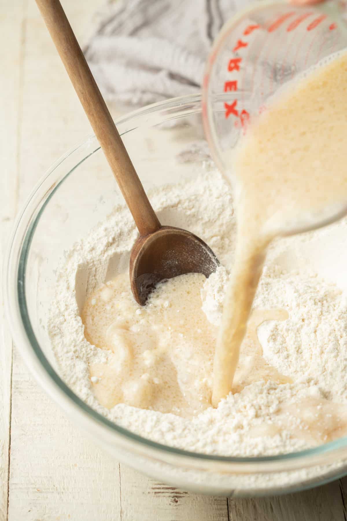 Liquid ingredients being poured into a bowl of dry ingredients for making muffin batter.