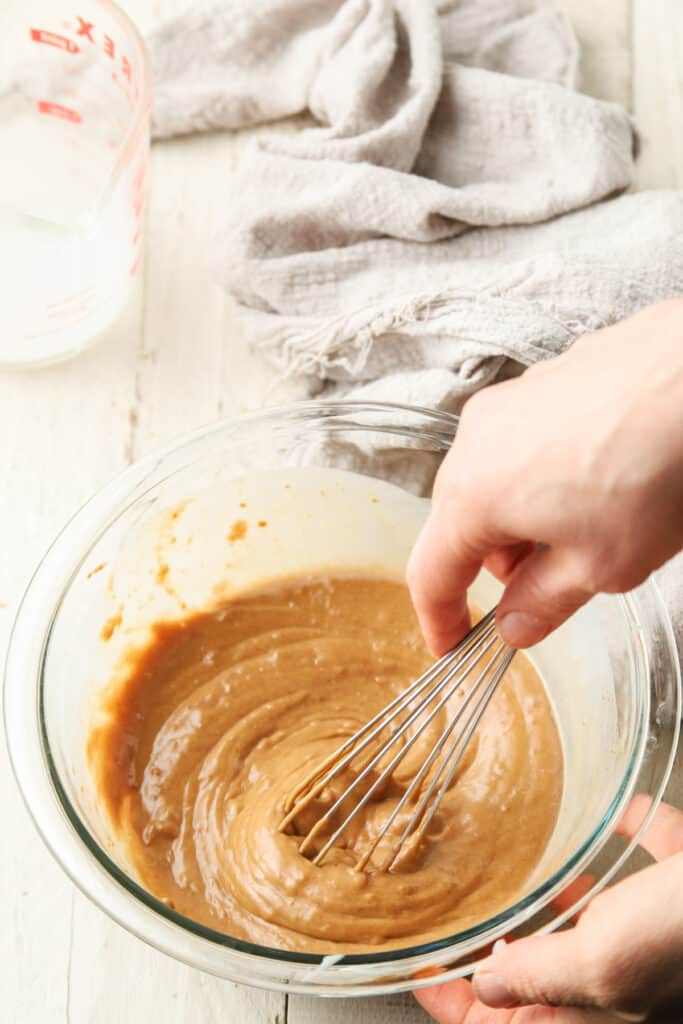 Hand whisking Vegan Peanut Sauce together in a bowl.