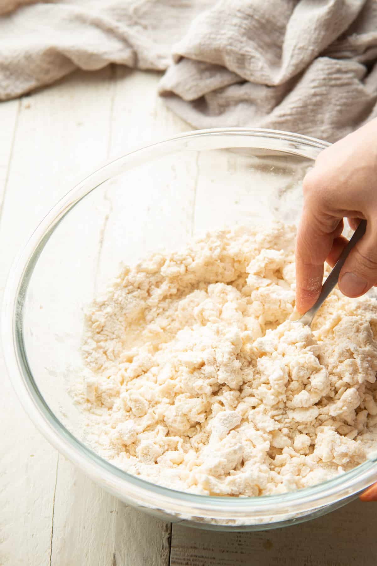 Hand stirring pastry dough together in a large bowl.