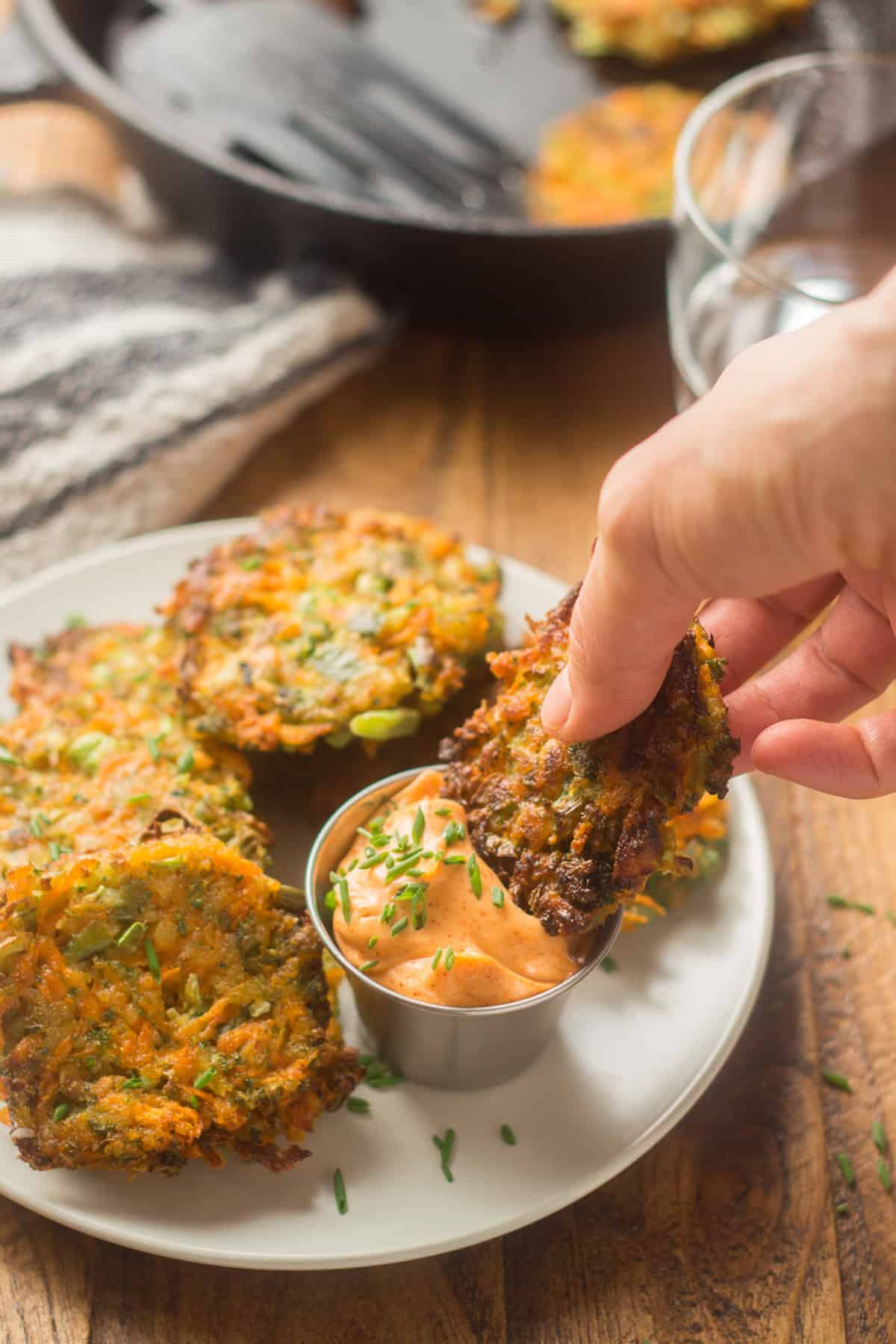 Hand dipping a Vegetable Fritter in a dish of chipotle mayo.