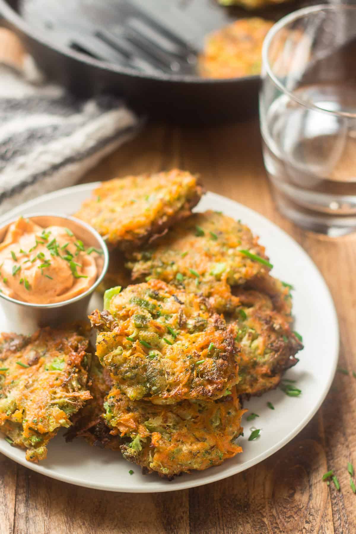 Plate of Vegetable Fritters with water glass and skillet in the background.