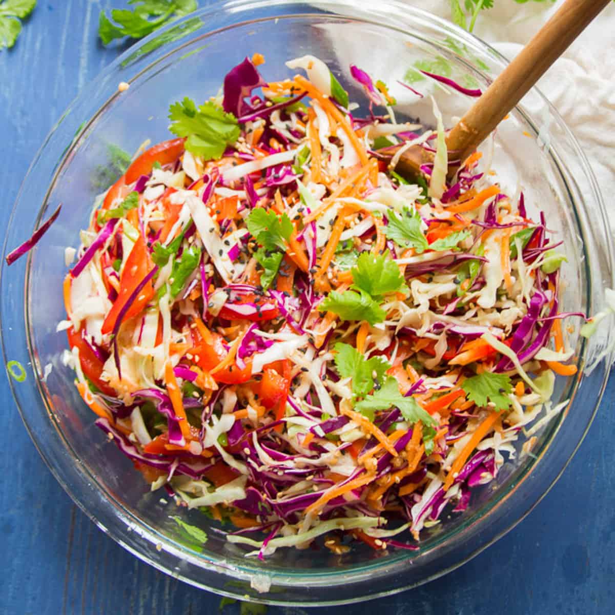 Bowl of Asian Slaw on a blue surface.