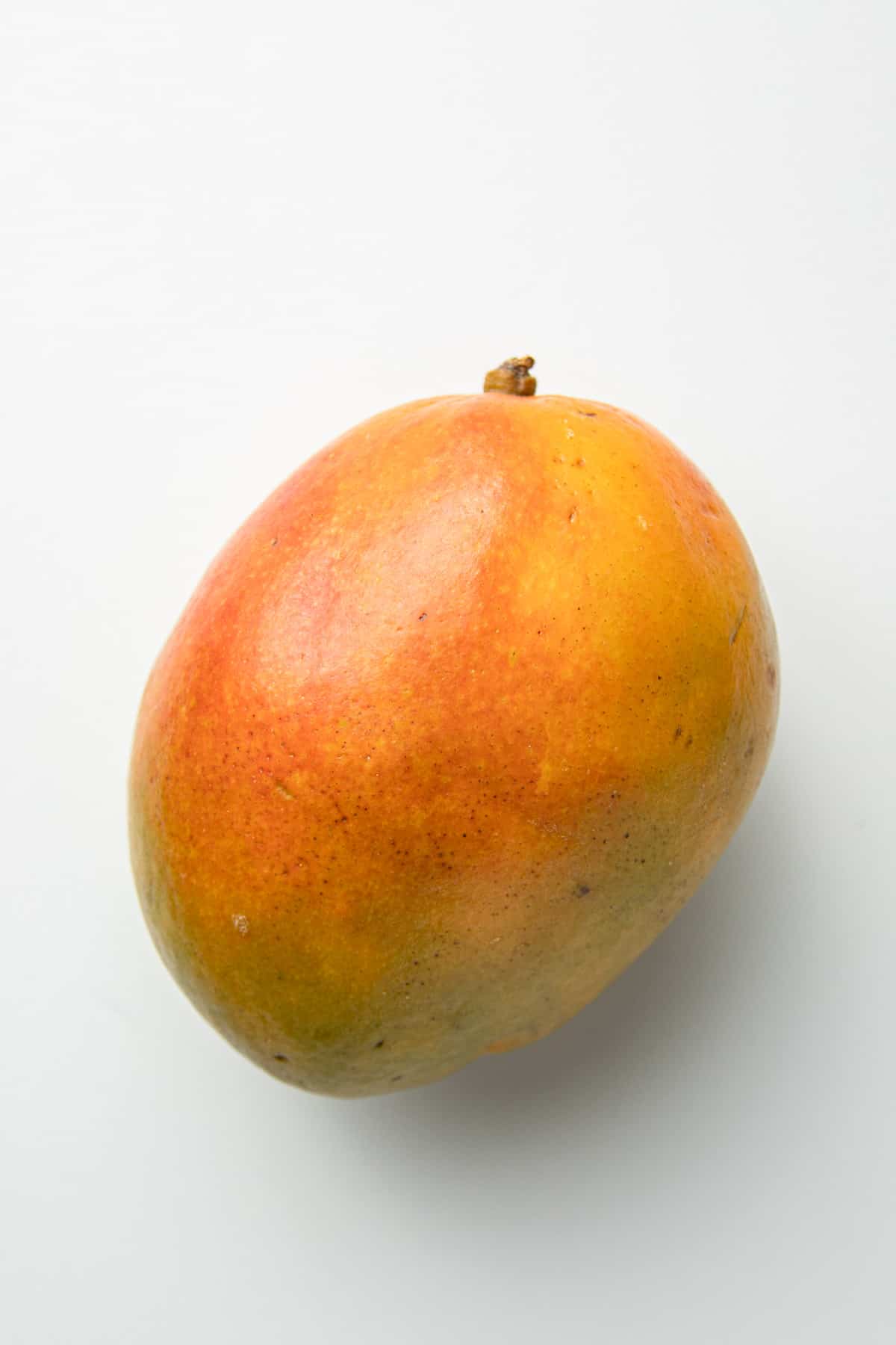Ripe Keitt mango on a white surface.
