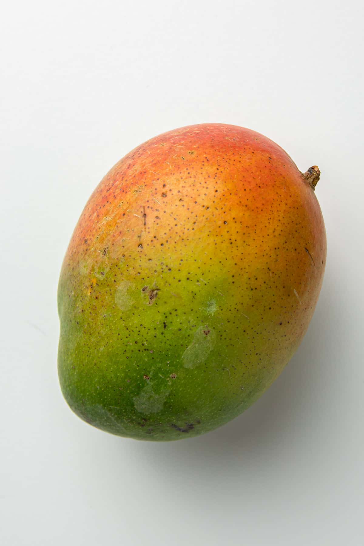 Unripe green mango on a white surface.