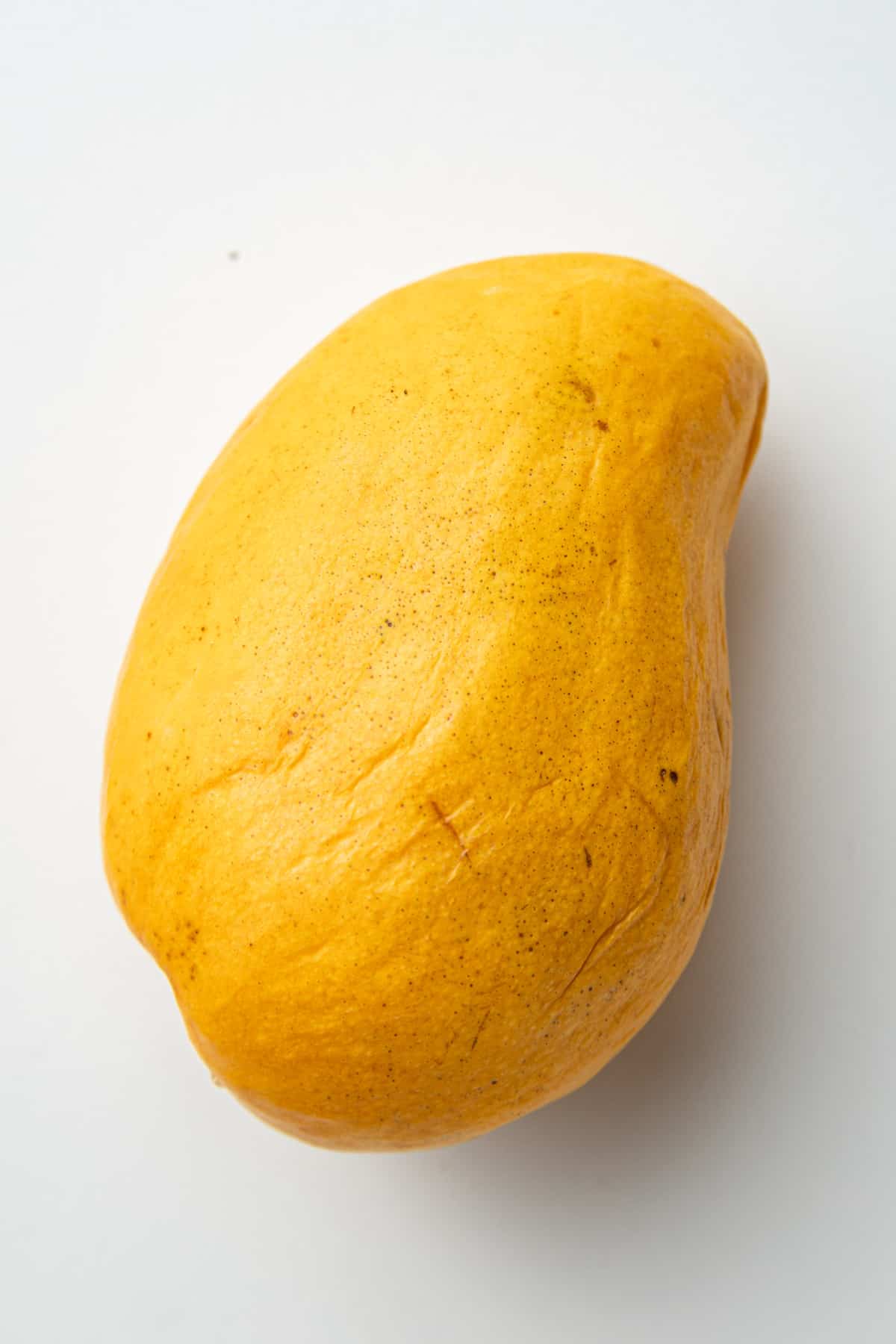 Ripe Ataulfo mango on a white surface.