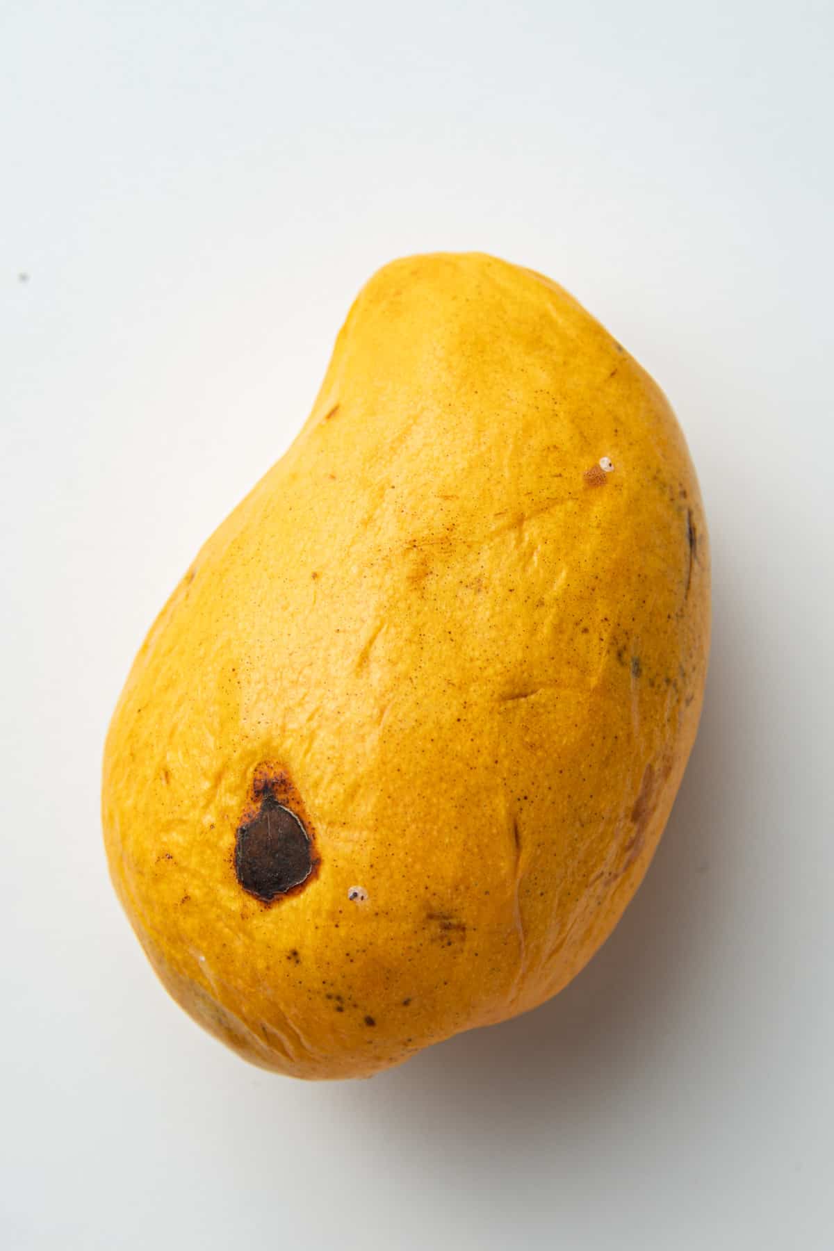 Ripe mango with a black spot on the surface.