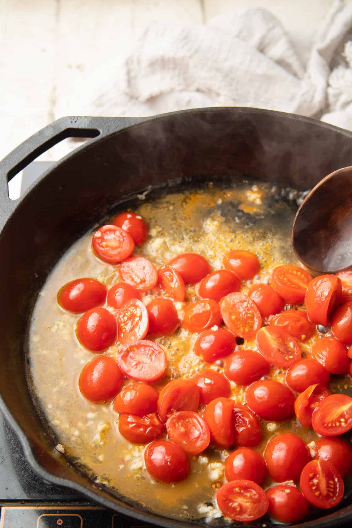 Cherry tomatoes and wine simmering in a skillet.