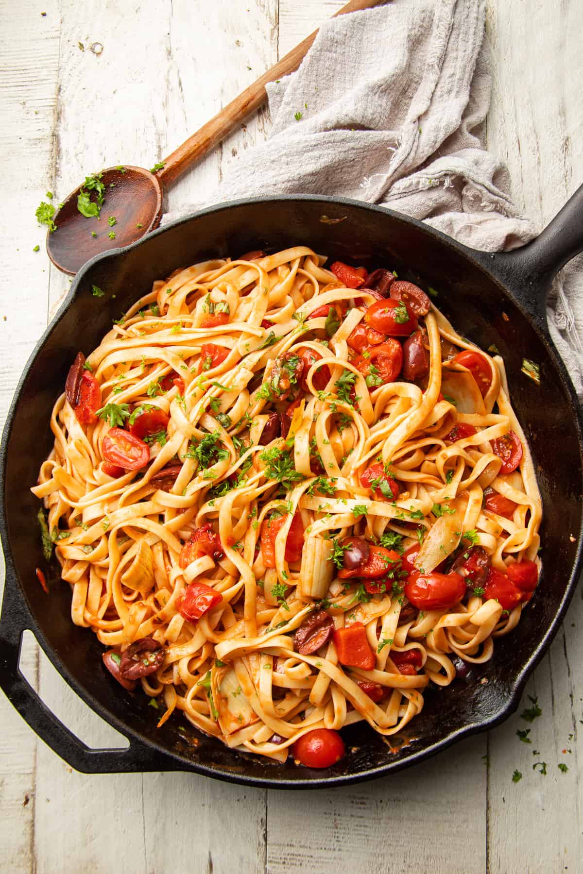 Skillet of Mediterranean Pasta with wooden spoon on the side.