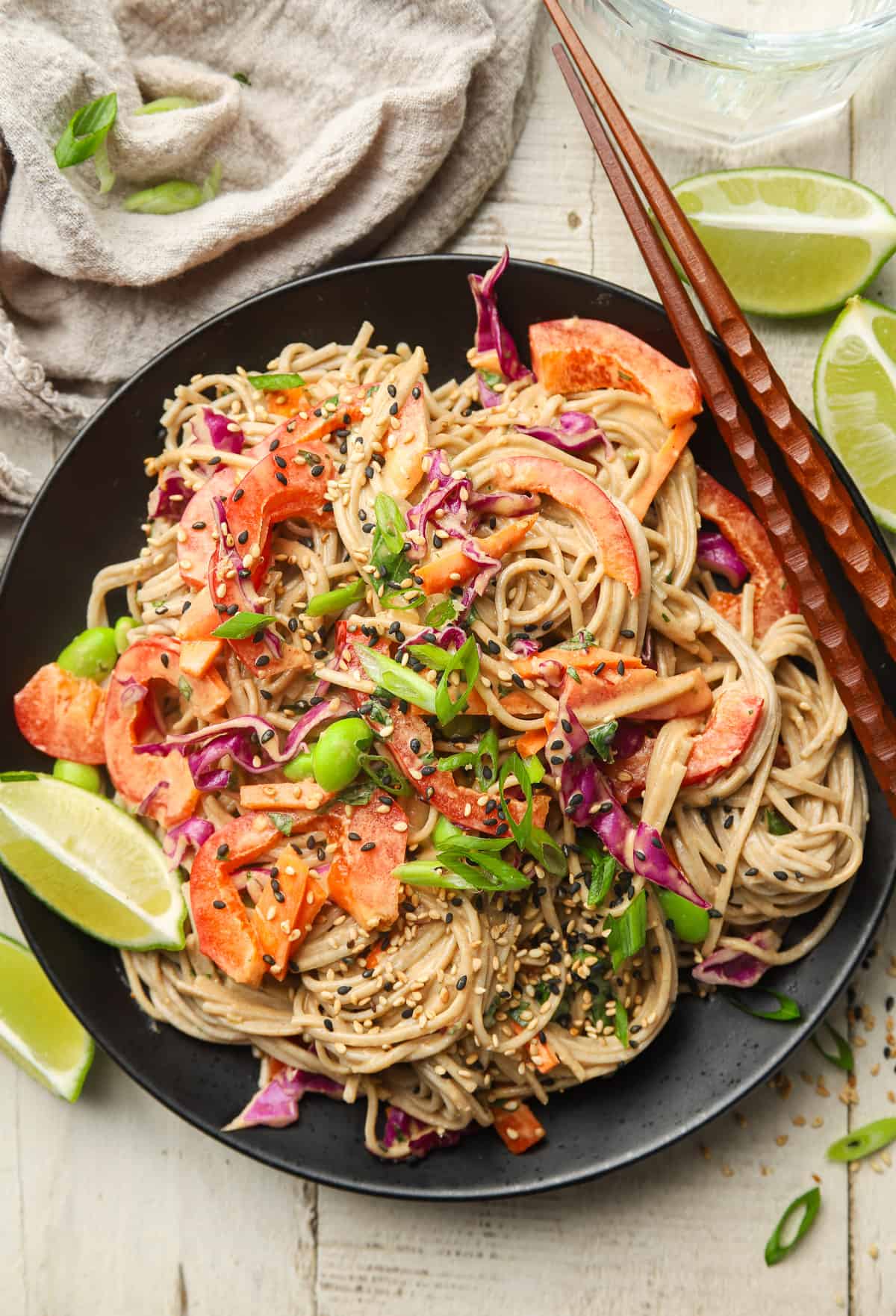 Vegan Soba Noodle Salad on a plate with chopsticks and lime wedges on the side.