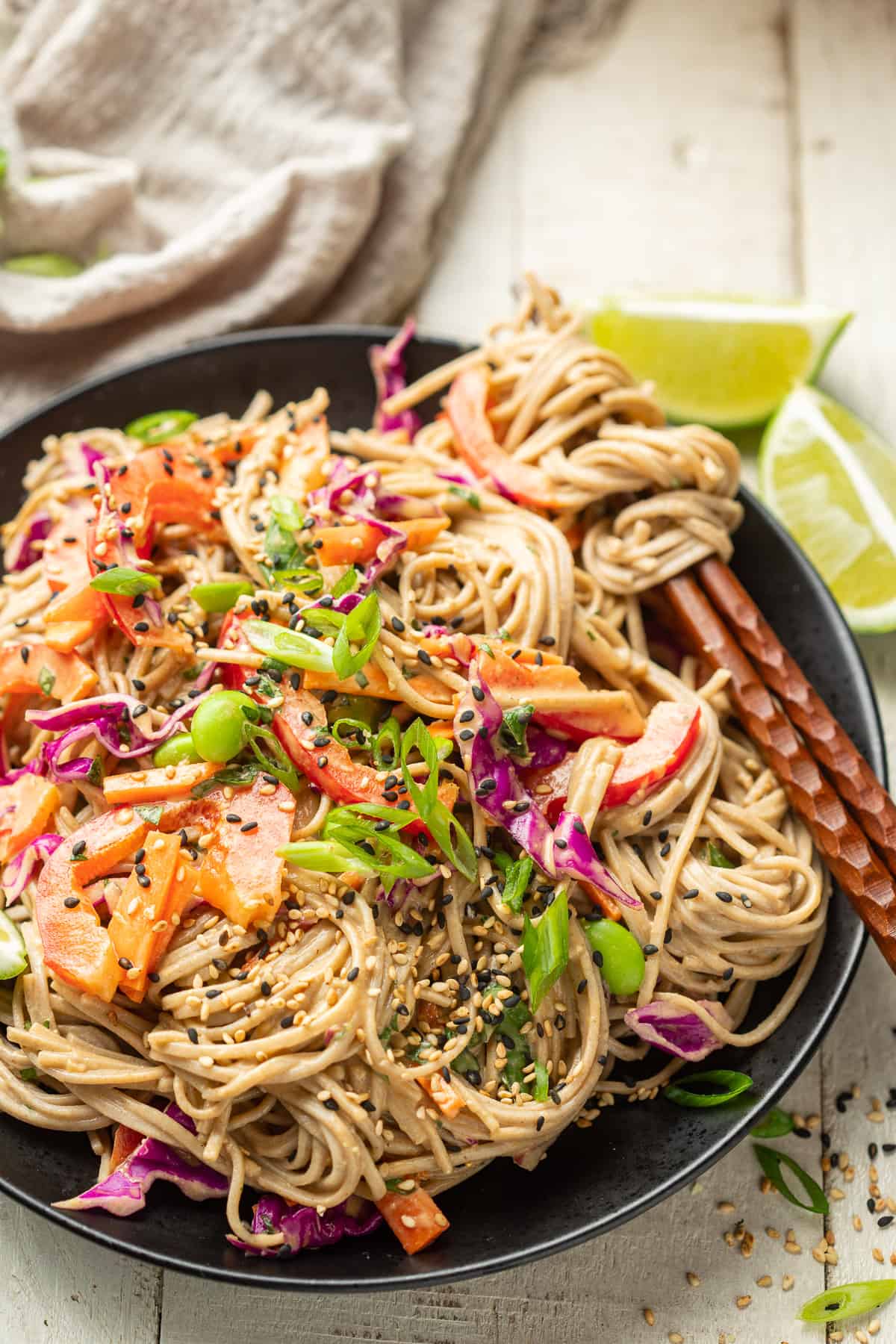 Vegan Soba Noodle Salad on a plate with a cluster of noodles wrapped around a pair of chopsticks.