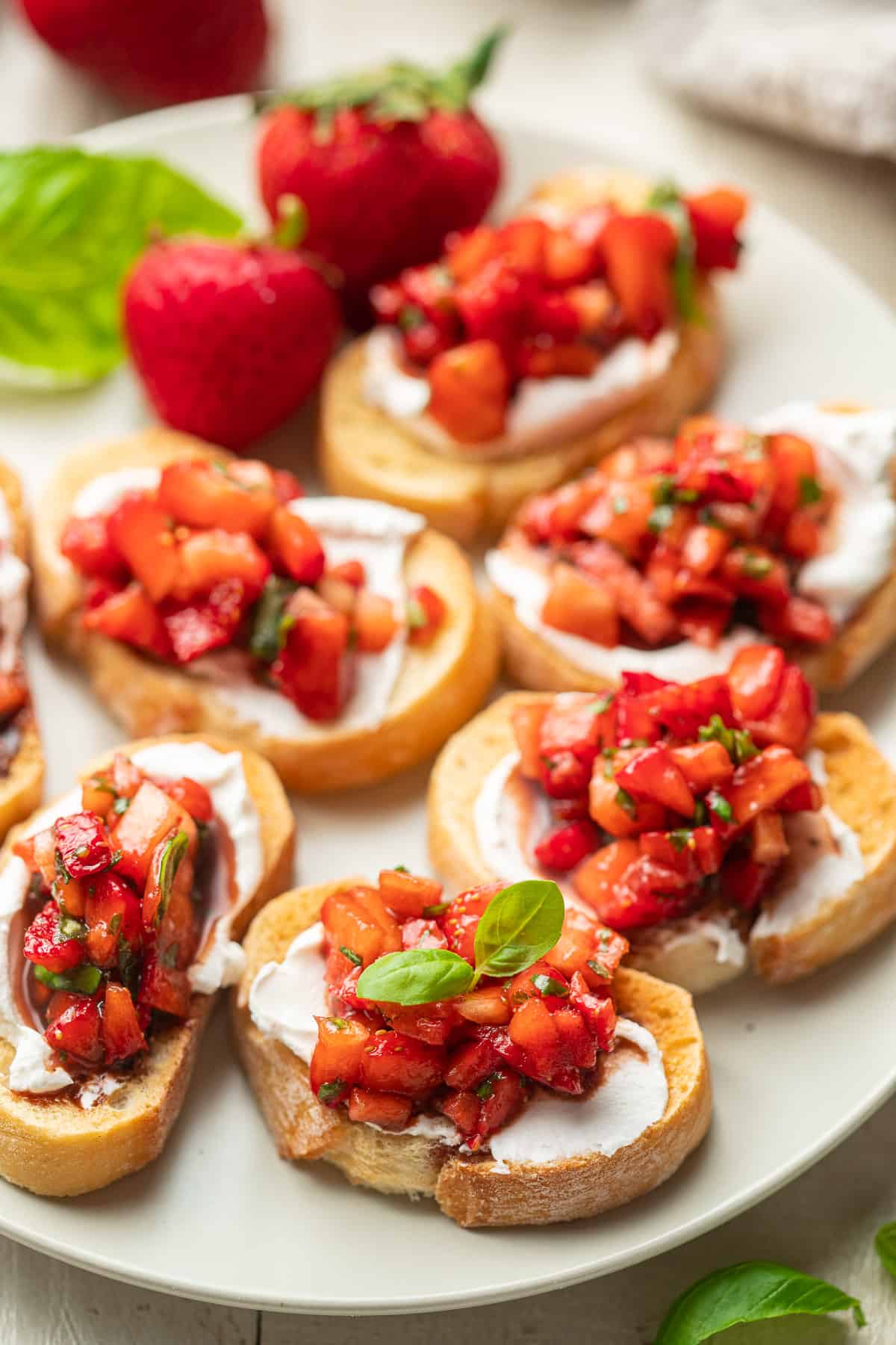 Baguette slices with vegan cheese and Strawberry Bruschetta arranged on a plate.