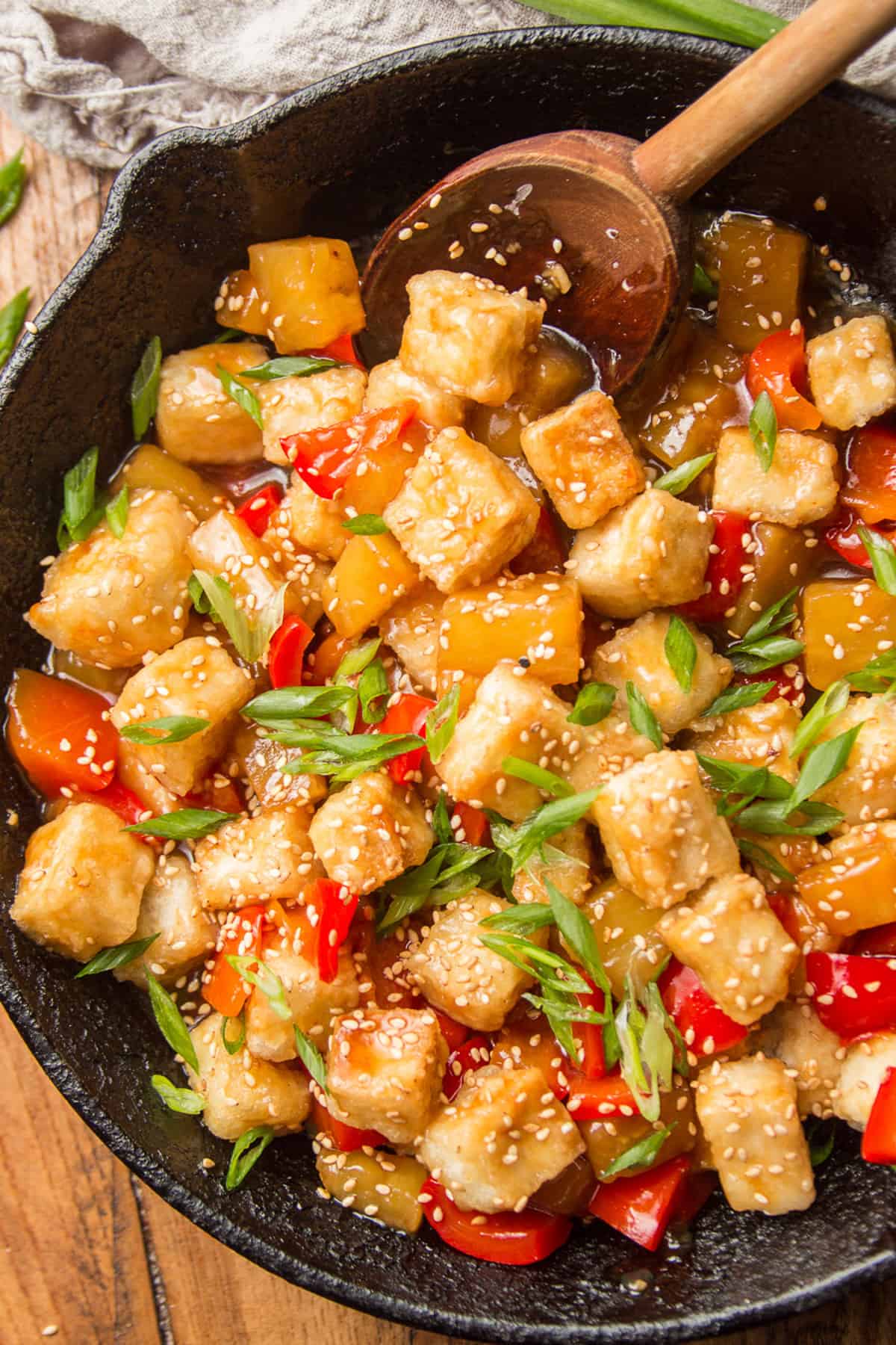 Skillet of Sweet & Sour Tofu with a wooden spoon.