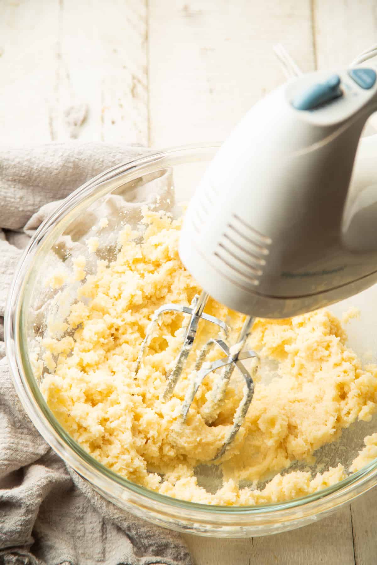 Electric mixer creaming butter and sugar in a mixing bowl.