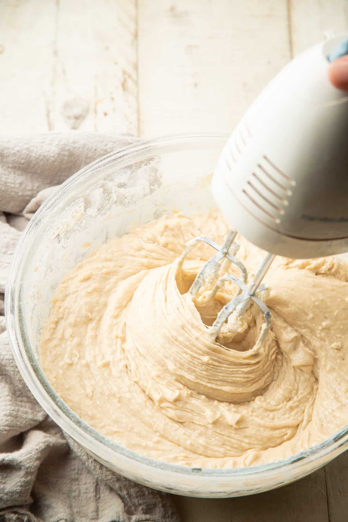 Electric mixer beating cake batter in a mixing bowl.