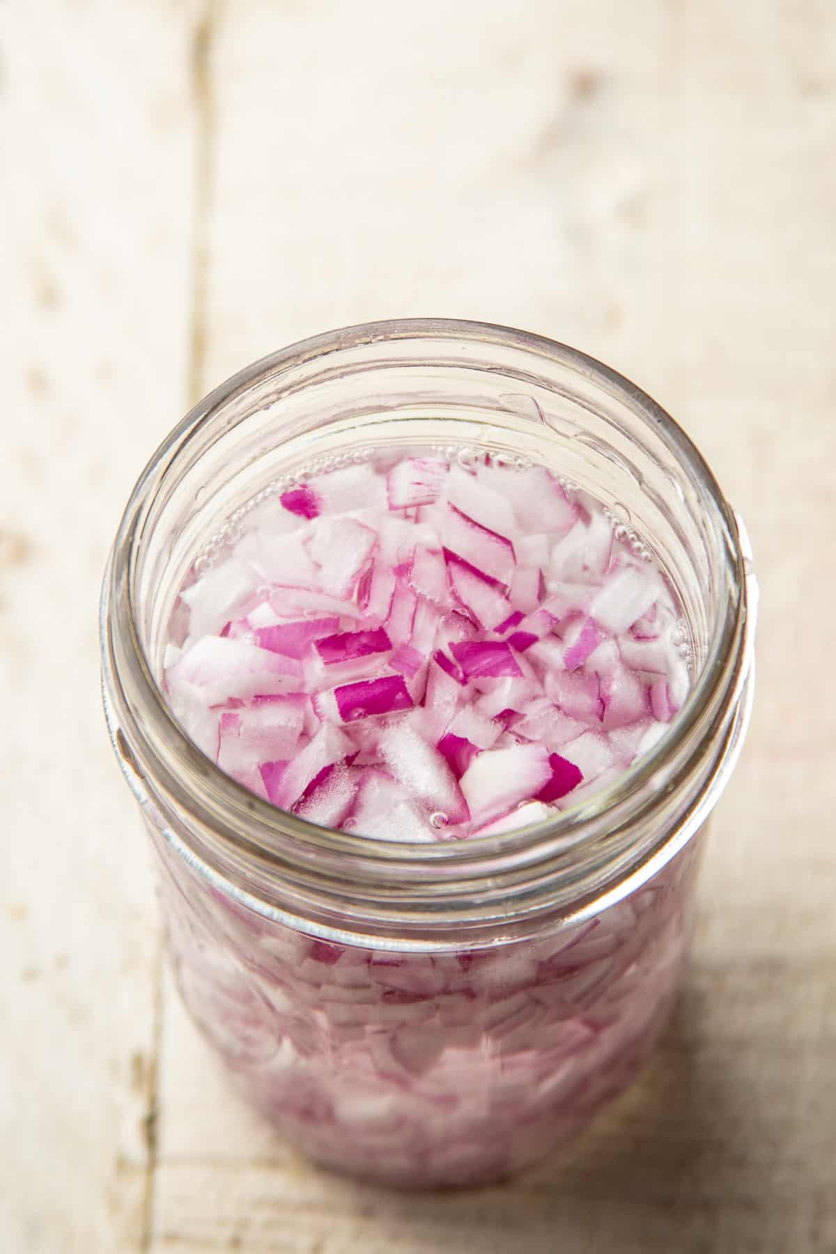 Diced red onion soaking in a glass of water.