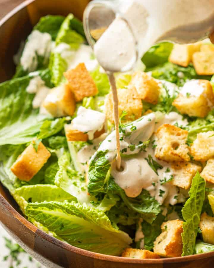Vegan Caesar Salad with dressing being drizzled over it.