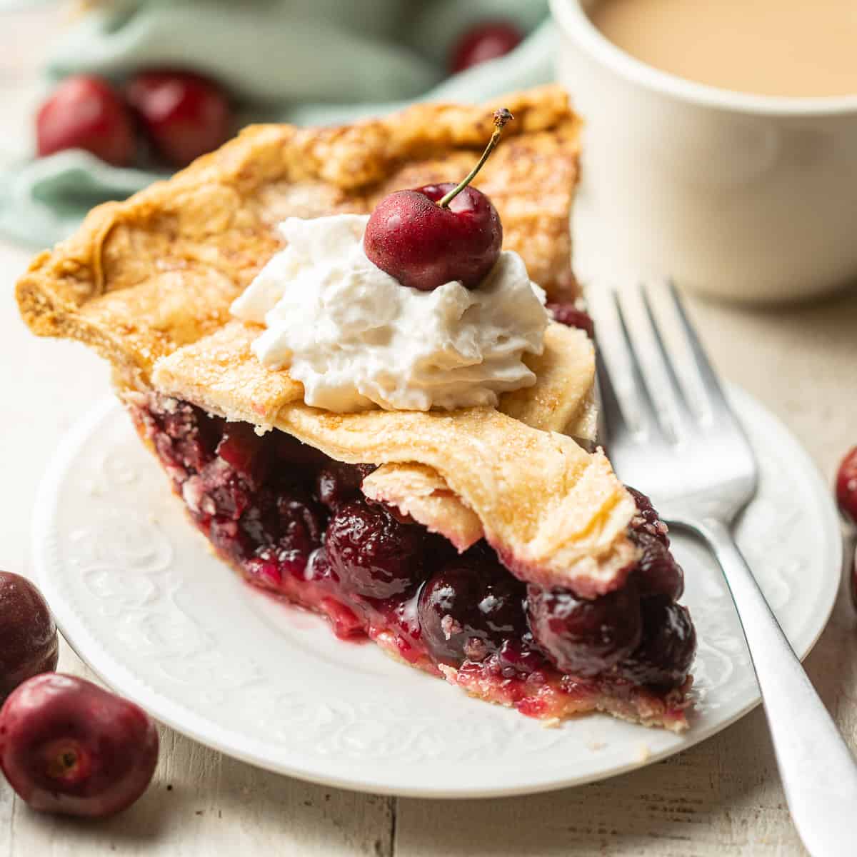Slice of Vegan Cherry Pie on a plate with whipped cream and a cherry on top.